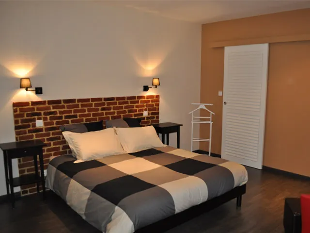 Chambre Voyage : le lit devant le mur de briques